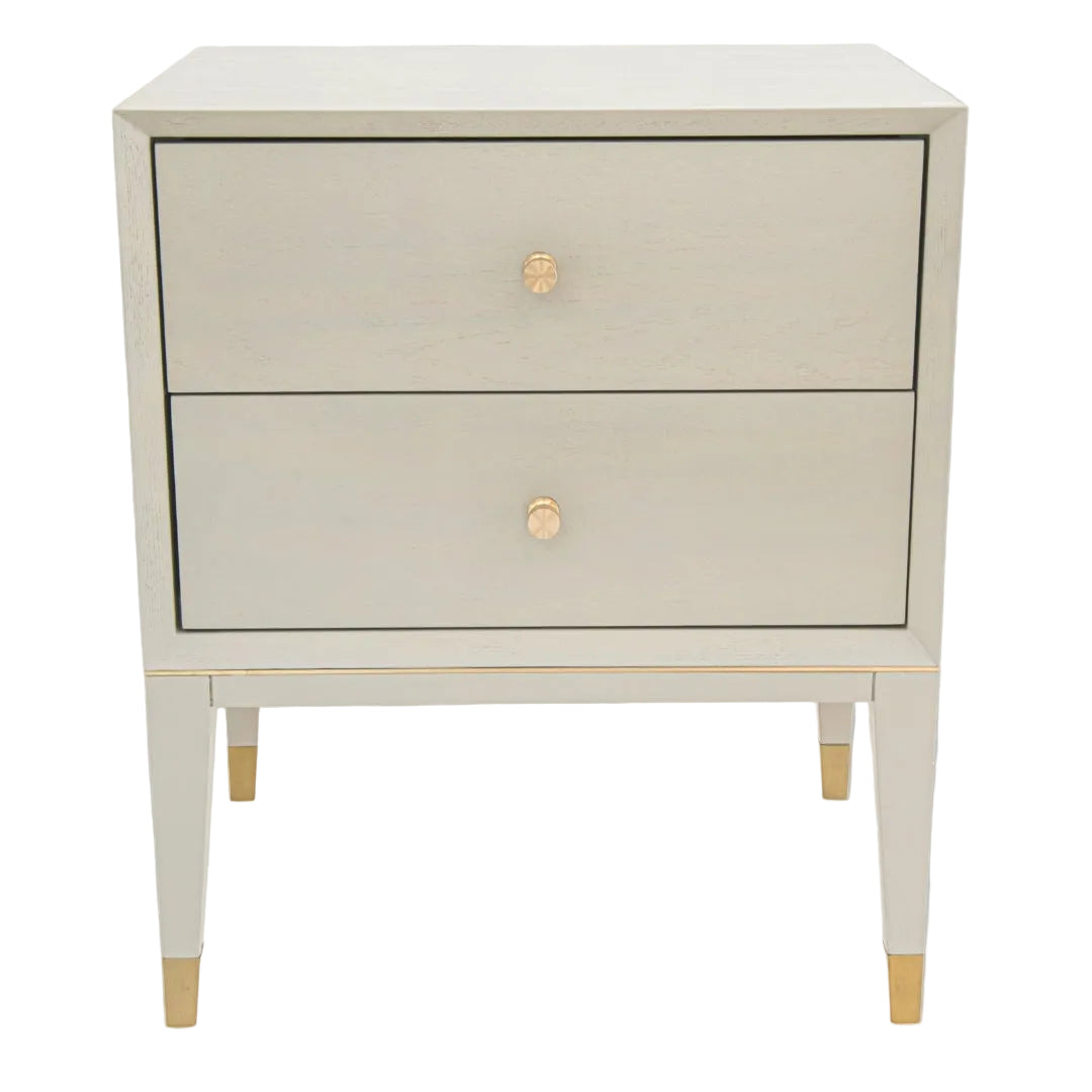 A ceramic grey side table with brass trim and gold-colored legs, featuring two drawers with gold handles.