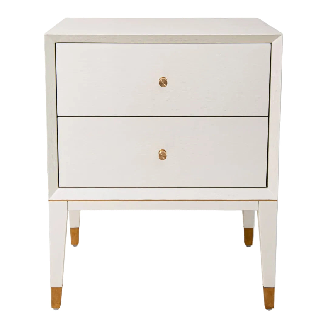 A white side table with brass trim and two drawers, placed on a plain background.