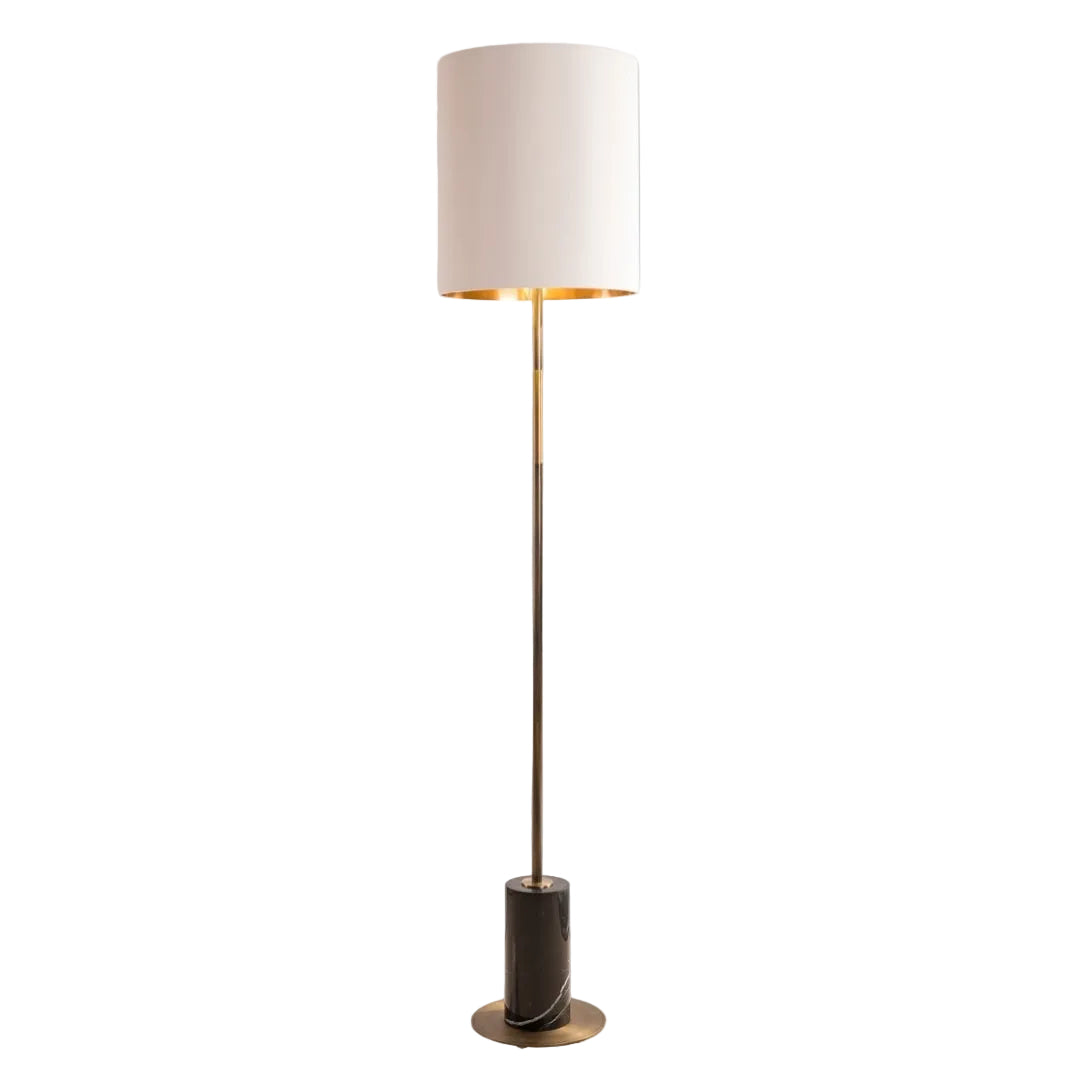 A contemporary floor lamp with an antique brass base and a black marble plinth, featuring a sleek stand and a white fabric lampshade.