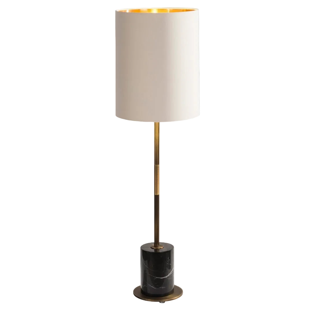 A contemporary table lamp with an antique brass base and black marble plinth, featuring a thin stand and opal fabric shade.