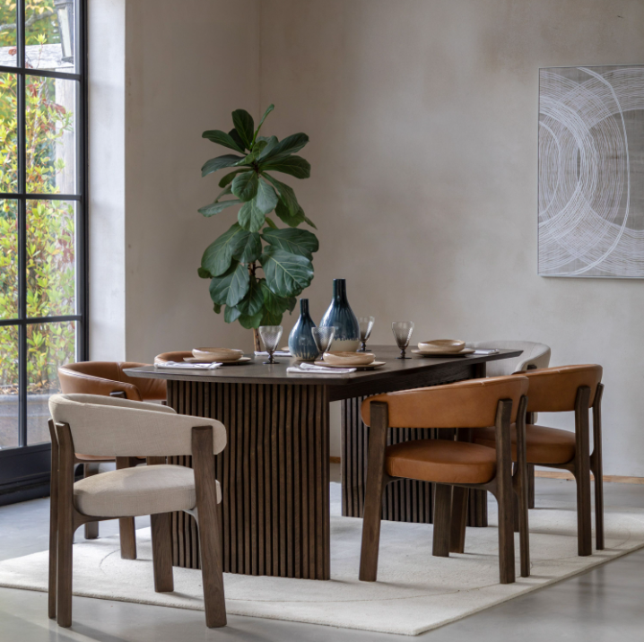 Dining room with a wooden table and chairs, featuring a plant and decorative items.