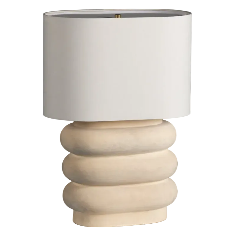 A table lamp with a matte white cylindrical shade and a sculptural, ribbed cream-colored base, shown against a plain white background.