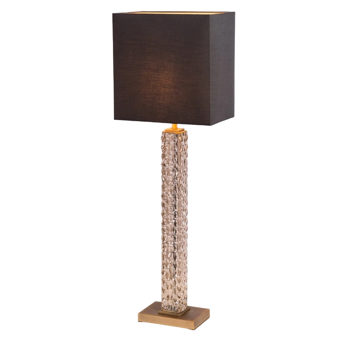 A sophisticated table lamp with antique brass detailing and a textured cognac glass base, topped with a charcoal fabric shade, providing a warm and inviting glow.