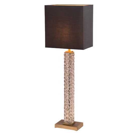 A sophisticated table lamp with antique brass detailing and a textured cognac glass base, topped with a charcoal fabric shade, providing a warm and inviting glow.