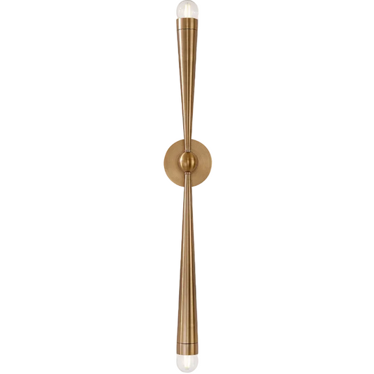 A modern wall-mounted light fixture with a brushed brass finish, featuring two long, tapered arms extending from a central round plate, each ending in a clear glass bulb.