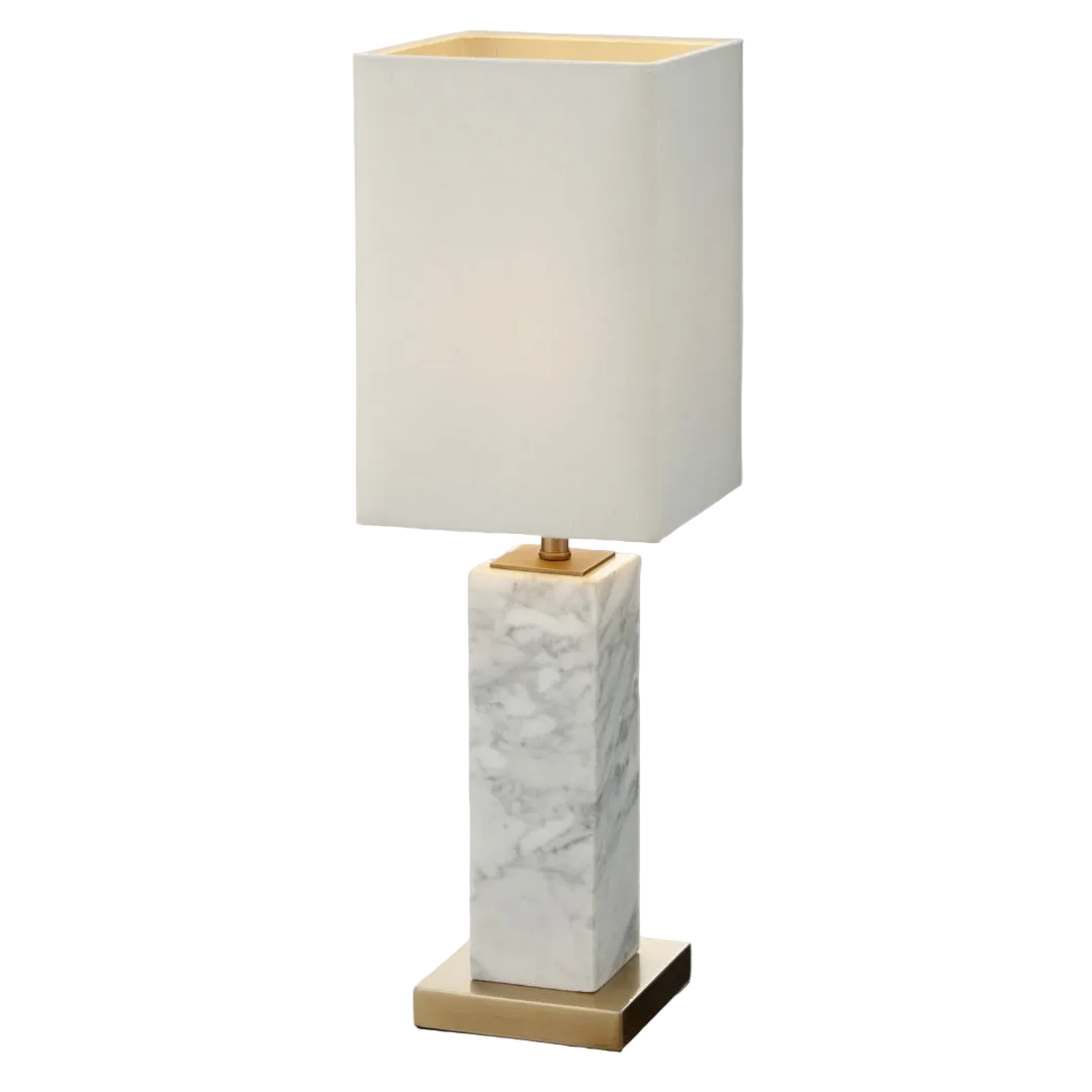 A petite table lamp with a white marble base and antique brass details, topped with an opal fabric shade.
