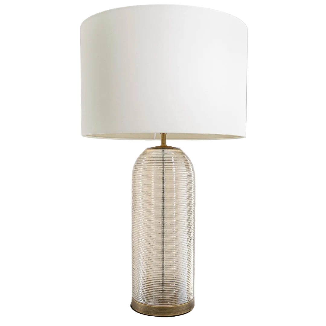 A Quince Table Lamp with a round antique brass base, textured cognac glass body, and an opal fabric shade.