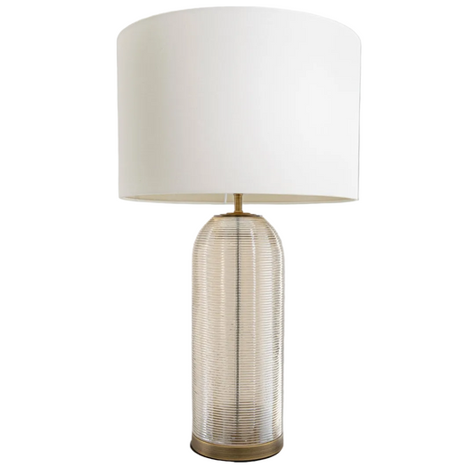 A Quince Table Lamp with a round antique brass base, textured cognac glass body, and an opal fabric shade.