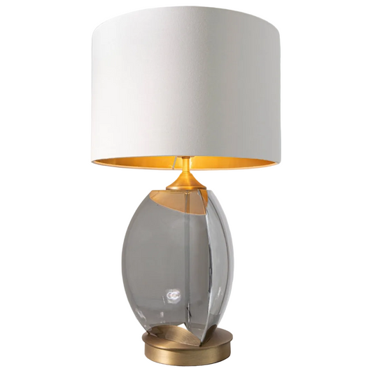A table lamp with a smoke glass base and antique brass accents, topped with an opal fabric shade lined with gold.