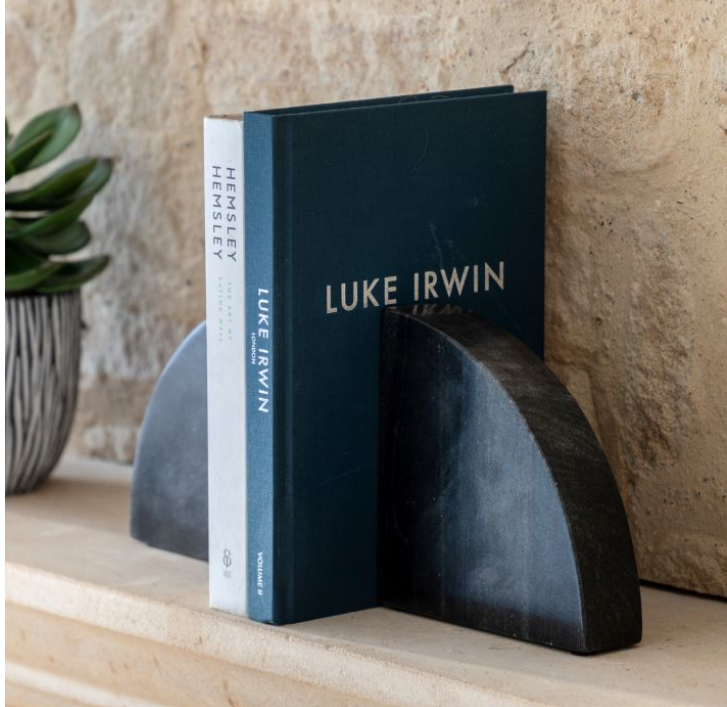 Bookends holding books with 'Luke Irwin' on a stone shelf.