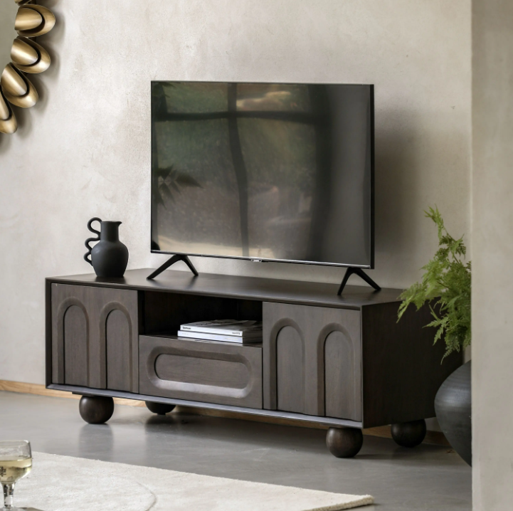 Modern TV stand with a television and decorative items in a living room setting.