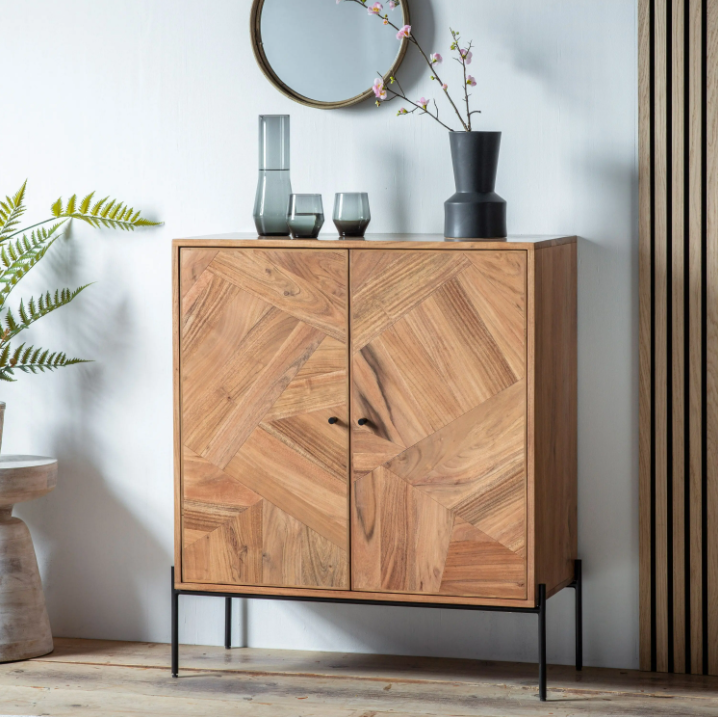 Wooden cabinet with a geometric pattern in a room with a plant and mirror.