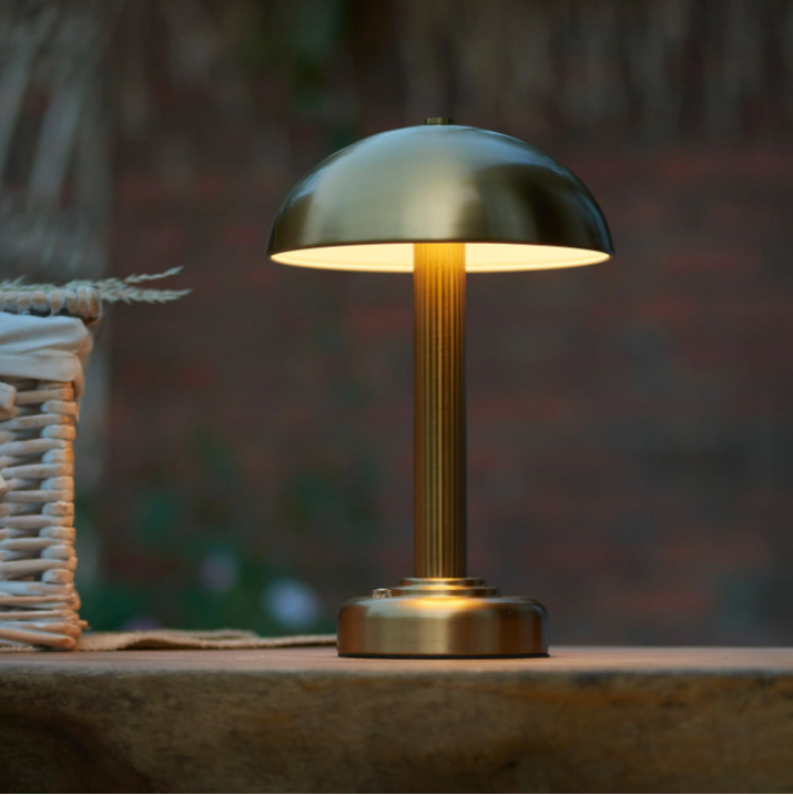 Gold table lamp on a wooden surface with a blurred background