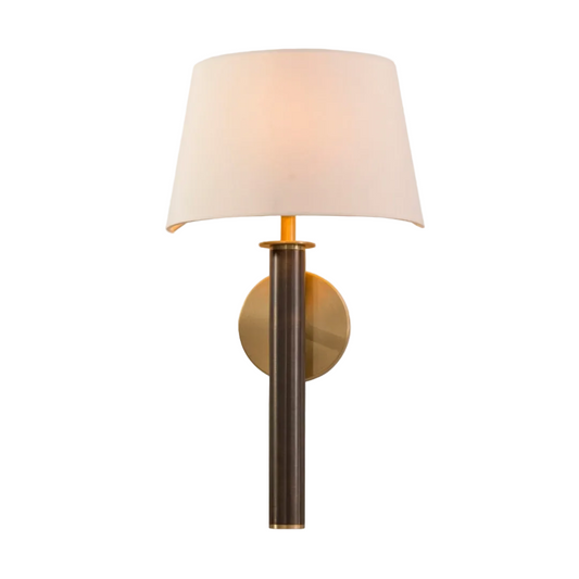 A wall lamp with a dark antique brass tube and base, paired with a light antique brass circular wall mount and an off-white fabric shade.