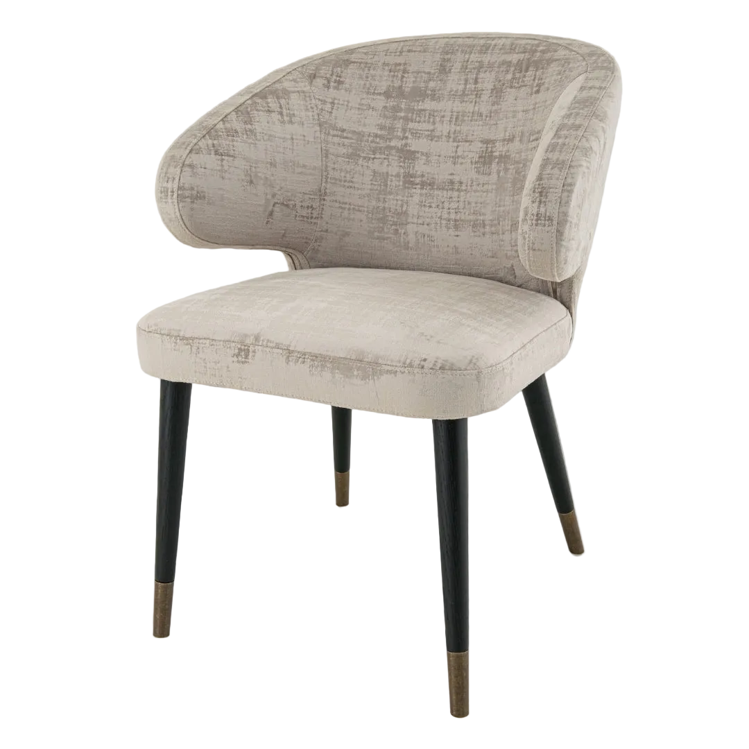 A luxurious upholstered chair with soft mushroom velvet fabric, having a painted black frame with antique brass accents, and dark wood legs with brass-capped feet.
